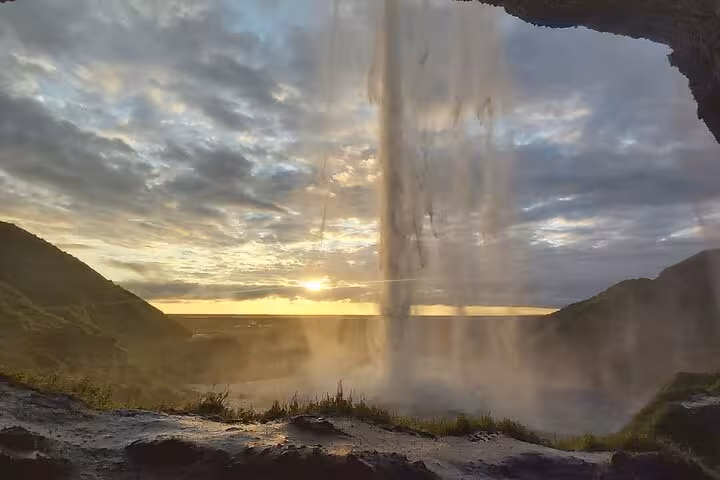 View from behind Seljalandsfoss waterfall at sunset on Iceland's South Coast