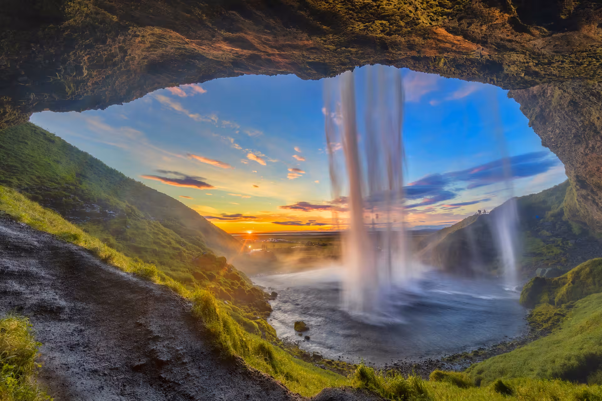 View from behind Seljalandsfoss waterfall at sunset on Iceland's South Coast