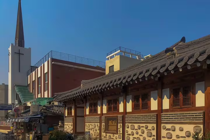 Traditional Korean hanok building with tiled roof beside a church steeple in Seoul neighborhood