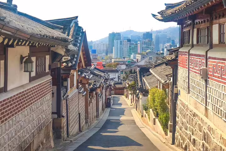 Traditional Korean hanok village alley in Seoul with modern city skyline in background