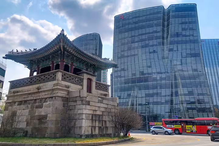 Traditional Korean bell pavilion contrasting with modern glass skyscrapers in Seoul city street