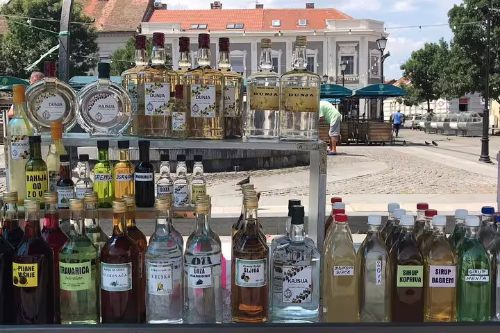 Traditional Serbian rakija bottles at Zemun market stall, a highlight on a private walking tour in Belgrade