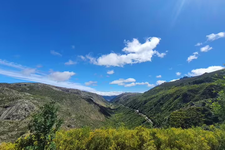 Lush green valleys and bright blue skies in Serra da Estrela, perfect for a summer tour.