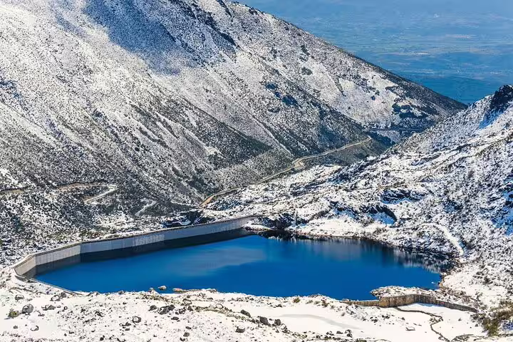 Snowy mountains and a blue lake in Serra da Estrela, ideal for a scenic winter excursion.