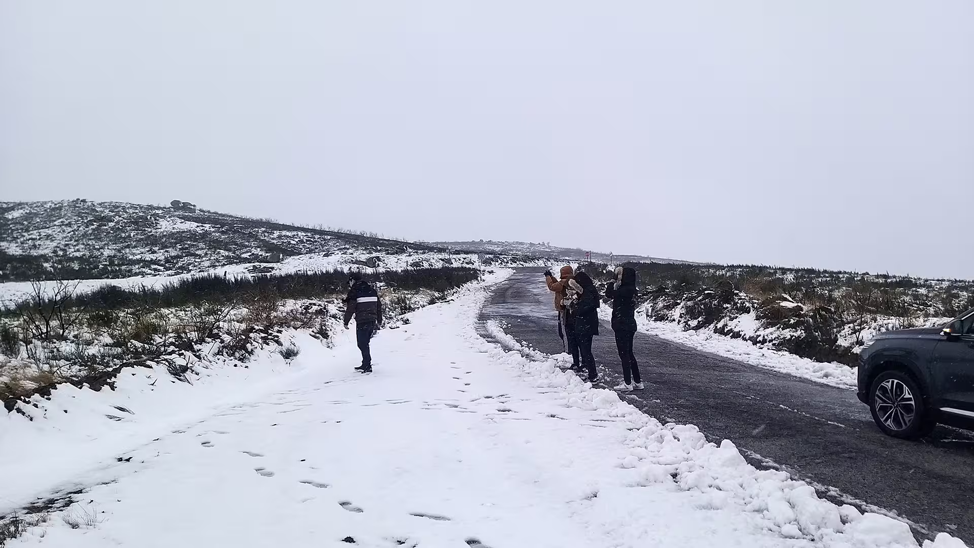 Tourists enjoy a snowy adventure in Serra da Estrela Park, capturing memories on a private tour with renowned local cheese tasting.