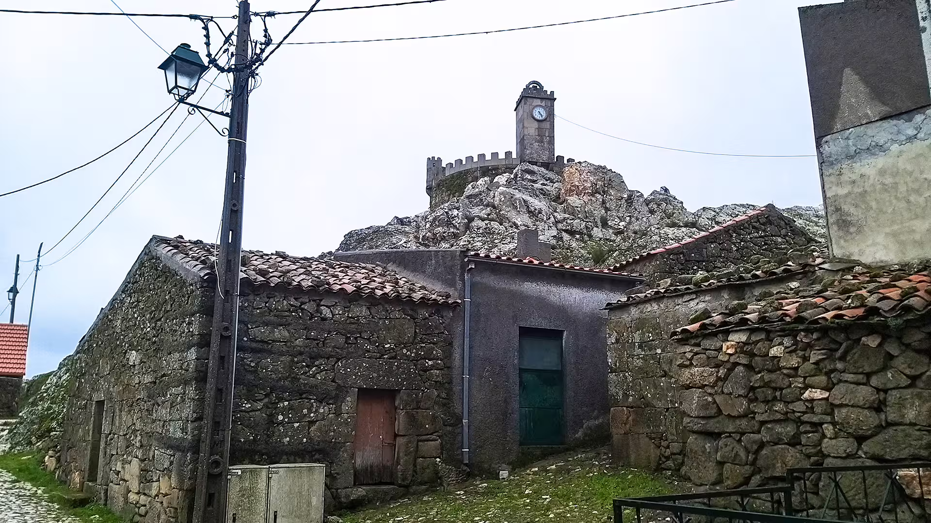 Rustic stone buildings and a historic clock tower in Serra da Estrela Park, perfect for exploring local culture and famous cheese.