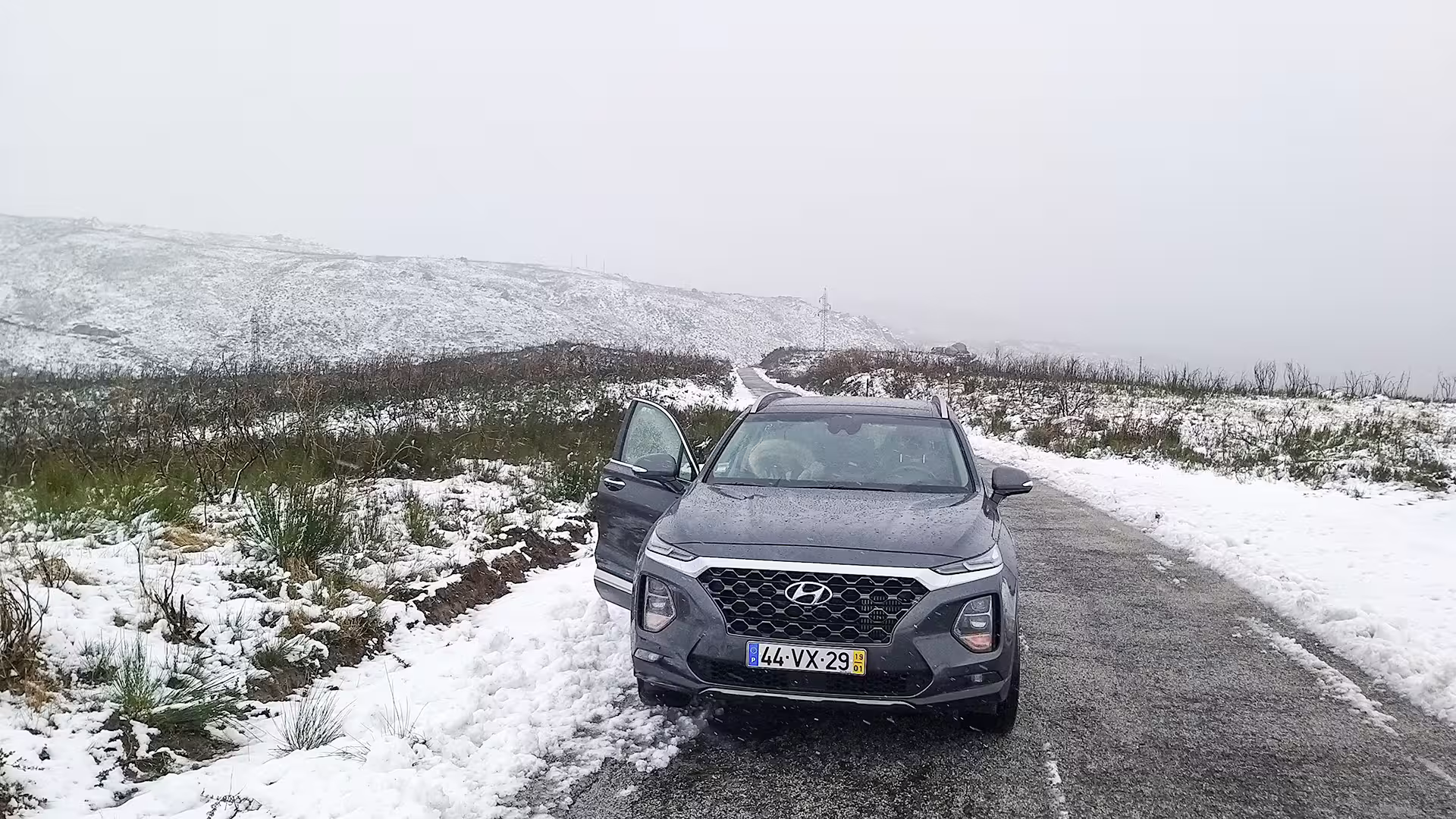 SUV parked on a snowy road in Serra da Estrela Park, offering scenic views and a unique cheese-tasting private tour experience.