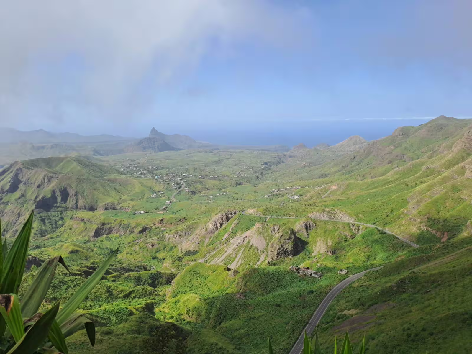 Lush green valleys and winding roads of Serra Malagueta Natural Park under a clear blue sky.
