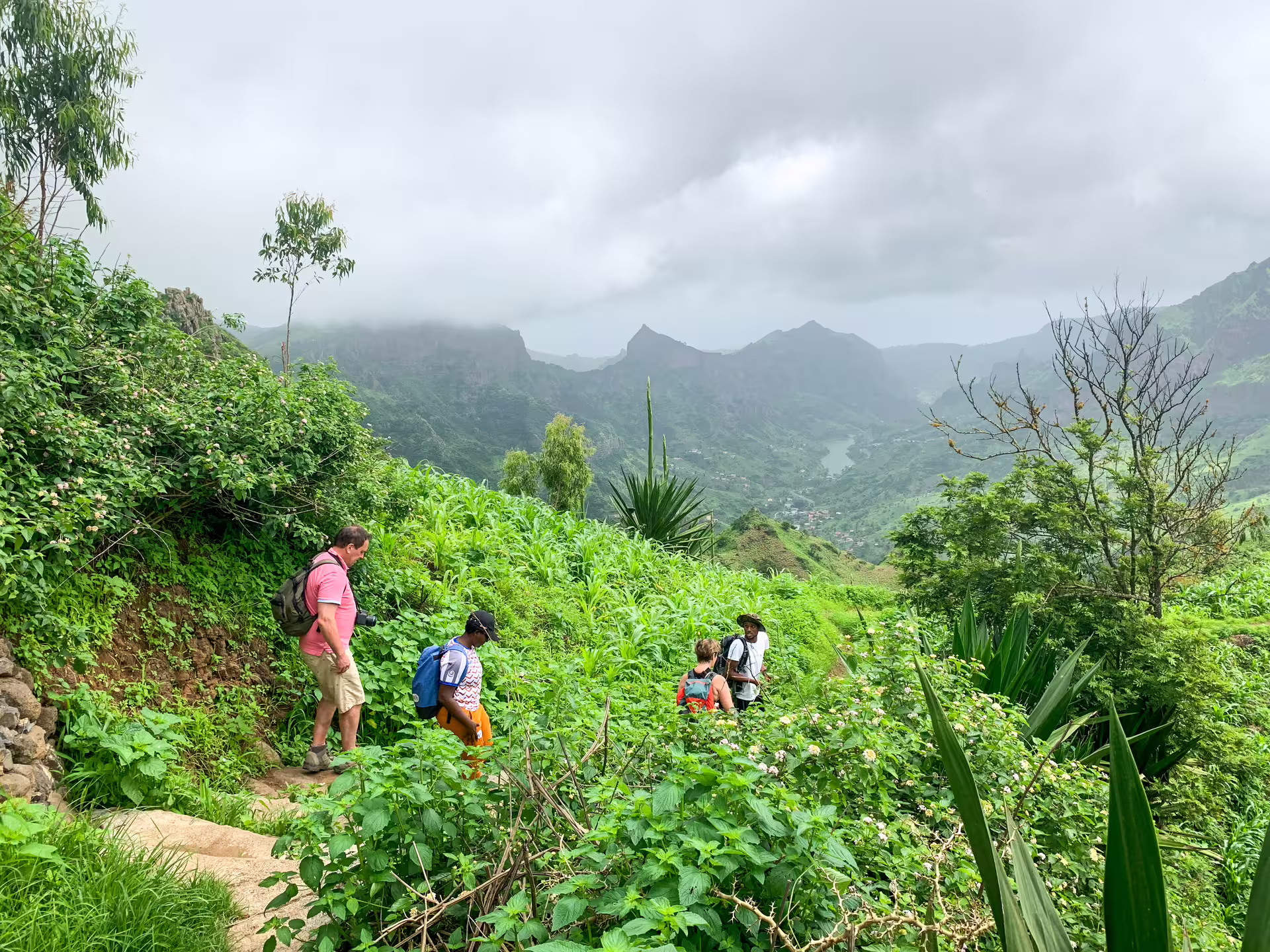 Hikers explore a verdant trail in Serra Malagueta with panoramic views of the lush Principal Valley below.