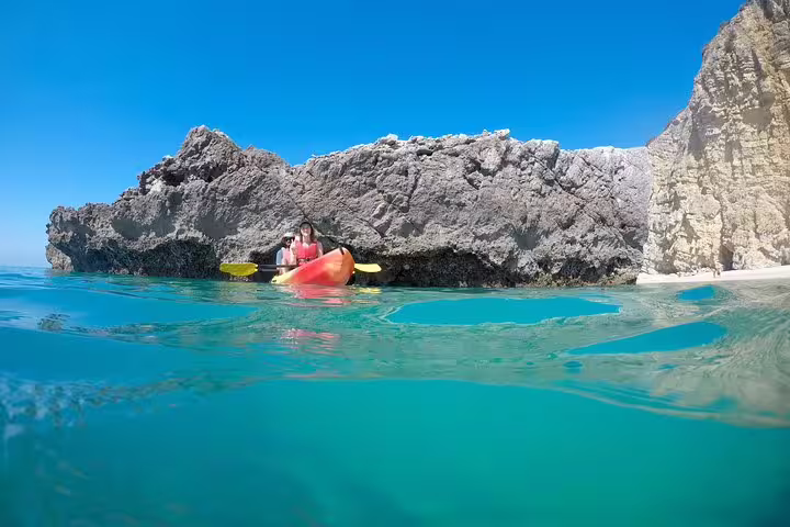 Kayakers explore crystal-clear waters and stunning rocky cliffs on a small group tour in Arrábida Natural Park, Sesimbra.