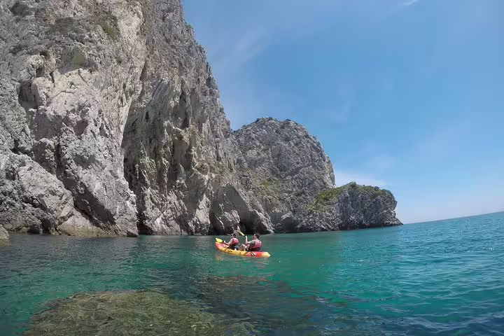 Kayakers explore the crystal-clear waters and stunning cliffs of Arrábida Natural Park during a Sesimbra small group tour.