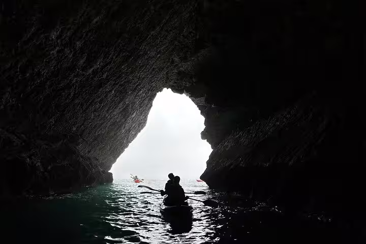 Kayakers explore a stunning sea cave on a small group tour in Sesimbra, Arrábida Natural Park, with shimmering turquoise waters.