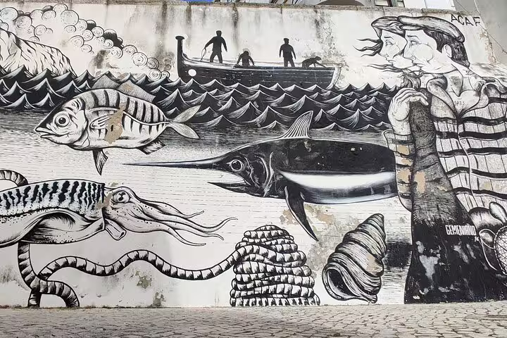 Vibrant mural in Sesimbra features ocean-themed art with fish, squid, and fishermen, capturing the essence of a coastal day tour.