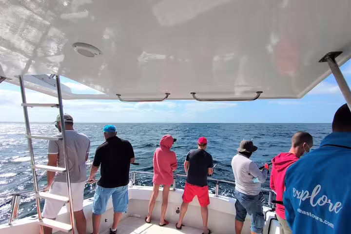 Group of anglers on a boat enjoying a sunny sport fishing tour in Sesimbra, showcasing the scenic ocean and clear skies.