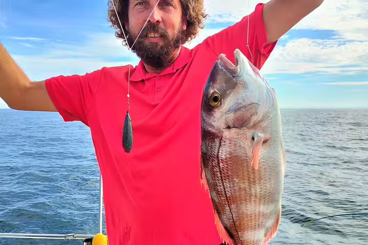Man proudly holding a freshly caught fish on a sport fishing tour in Sesimbra, showcasing the excitement of the all-inclusive experience.