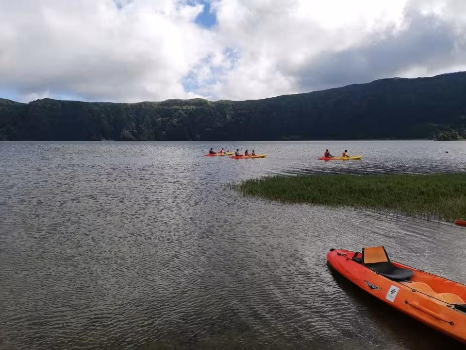 Colorful kayaks paddle across the calm crater lake of Sete Cidades on a full-day Jeep and kayaking adventure in the Azores