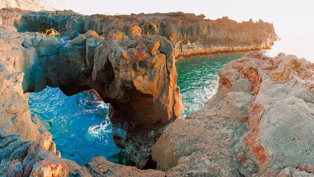 Sunlit volcanic cliffs and turquoise Atlantic waters frame Ferraria coastal lava arch on full-day Sete Cidades Jeep adventure