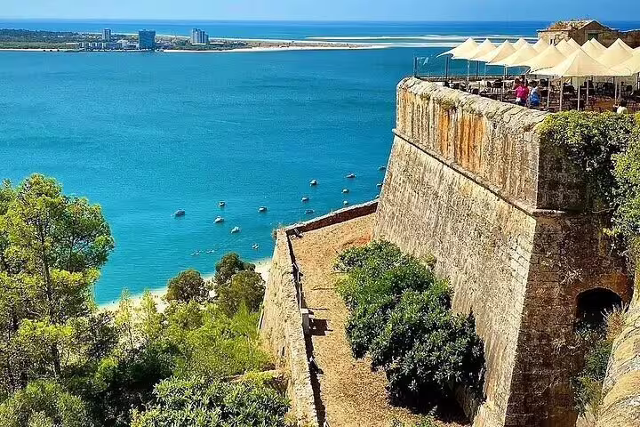 Discover Setúbal's stunning coastal view with historic castle walls overlooking the clear blue waters of the Atlantic.