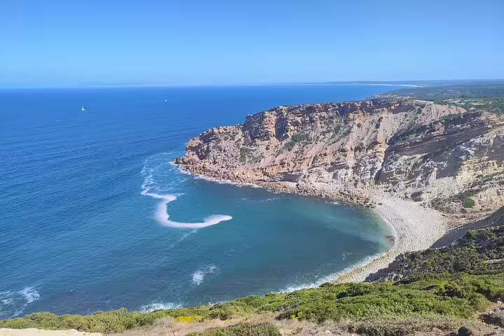 Scenic view of a rugged coastline with clear blue waters in Setúbal, perfect for nature and beach lovers.