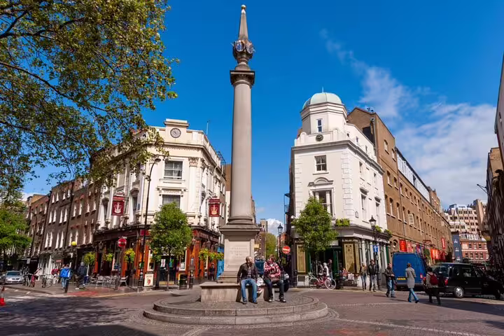 Seven Dials monument and street intersection in Covent Garden, London, with historic buildings and pedestrians