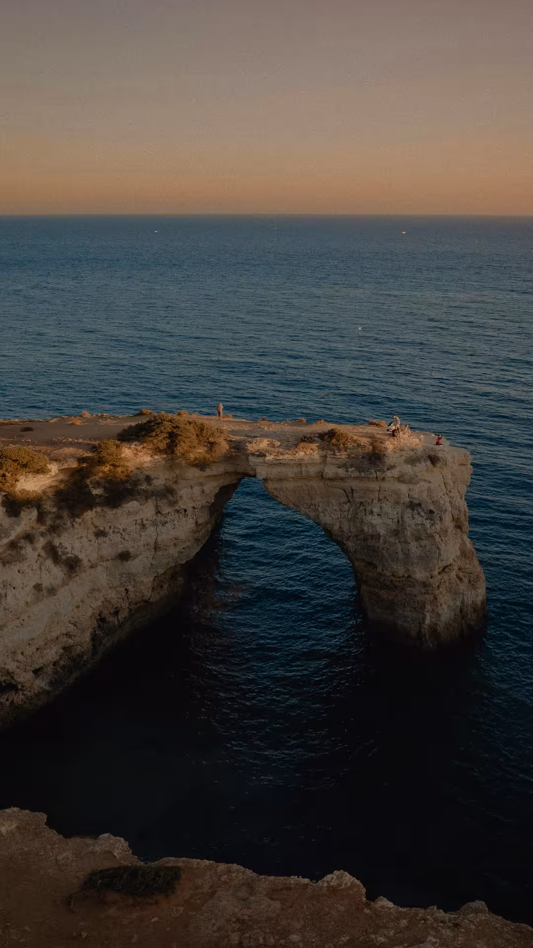 Sunset view of Algarve sea cliffs and natural rock arch along the Seven Hanging Valleys coastal bike tour route
