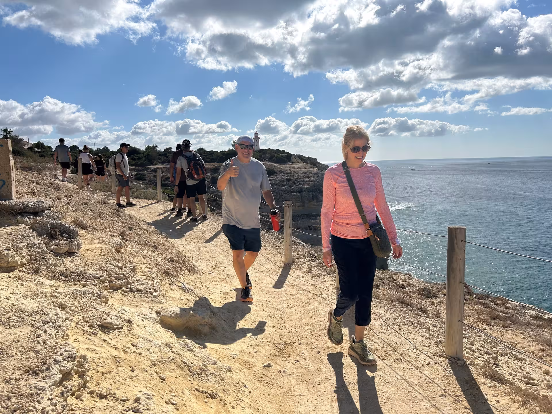 Hikers walking a sunny coastal cliff trail with ocean views on the Seven Hanging Valleys tour in Algarve