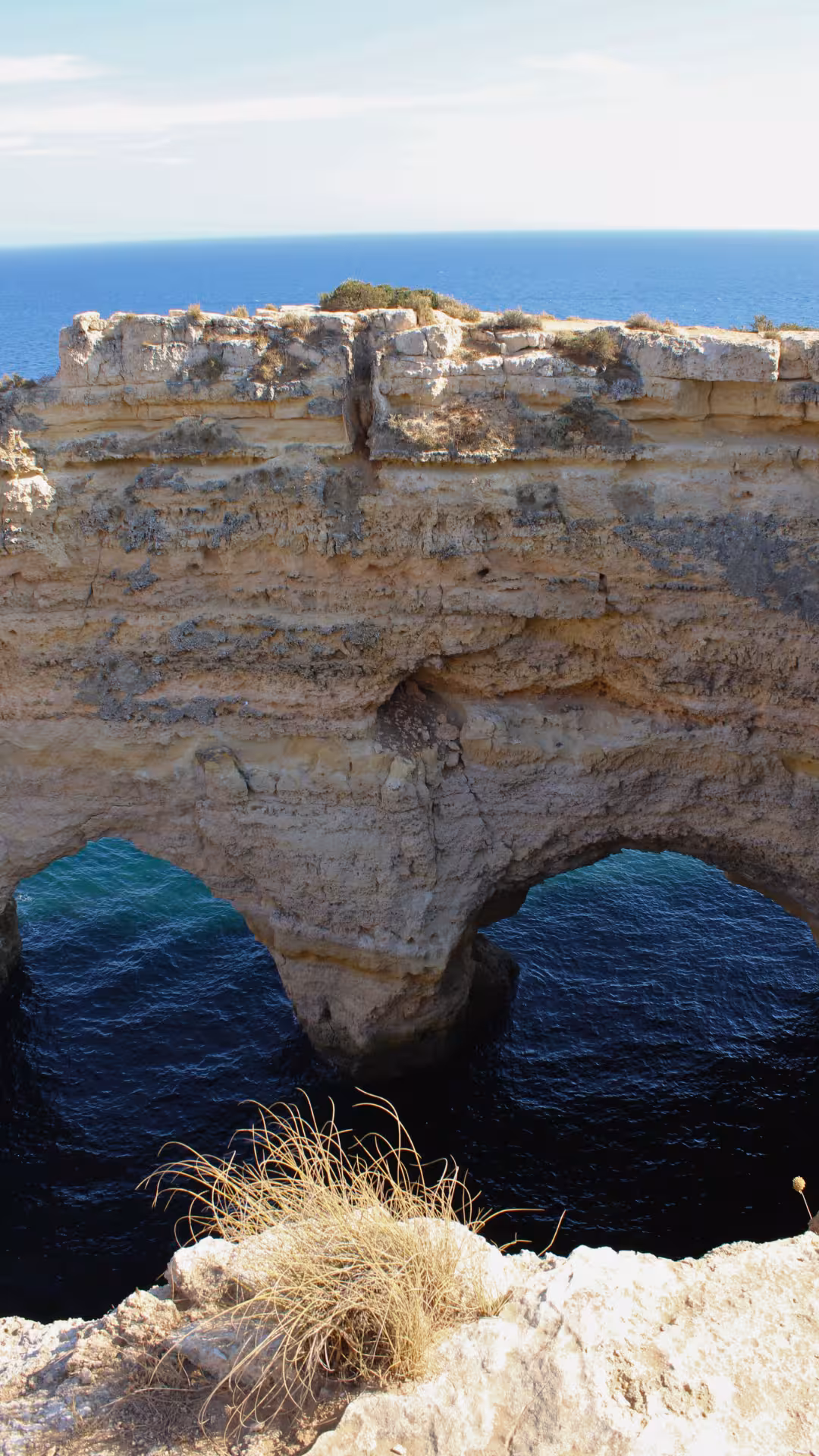Dramatic limestone sea arch and rugged cliffs above deep blue Atlantic waters on the Seven Hanging Valleys coastal bike route