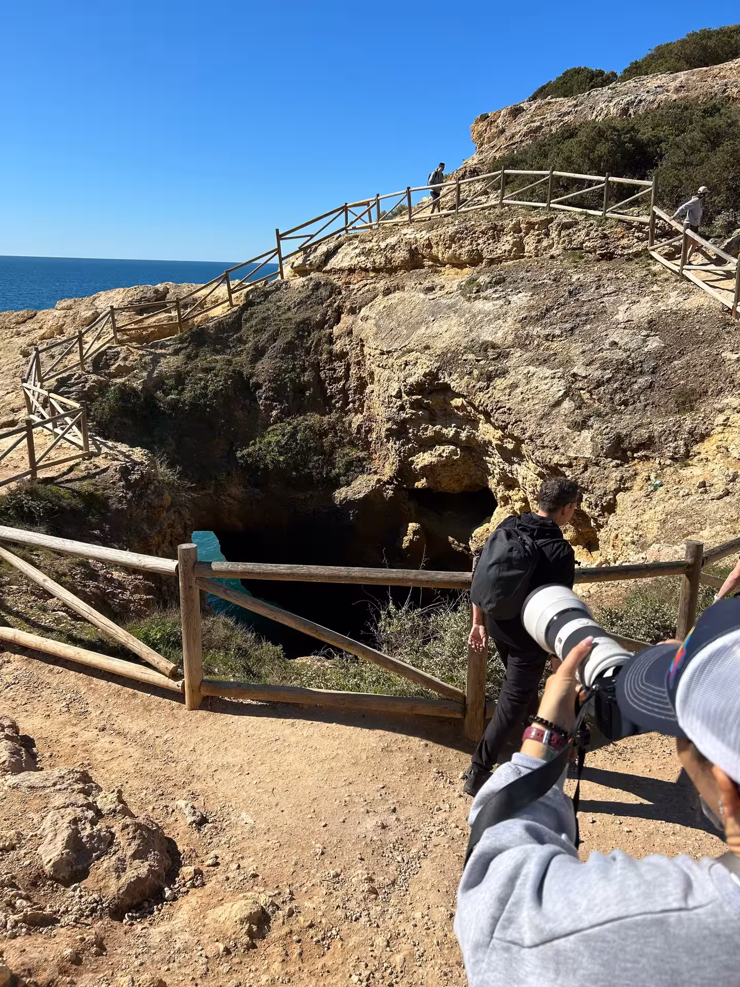 Tourists exploring a sea cave viewpoint on the Seven Hanging Valleys guided cliff walk trail in Algarve Portugal