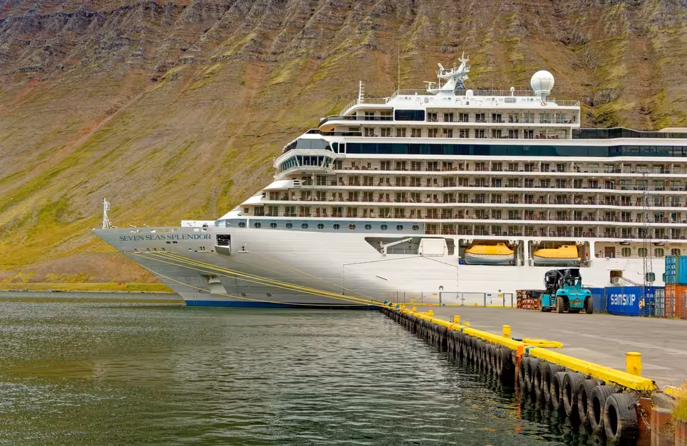 Seven Seas Splendor cruise ship docked at Westfjords port with green mountainside backdrop