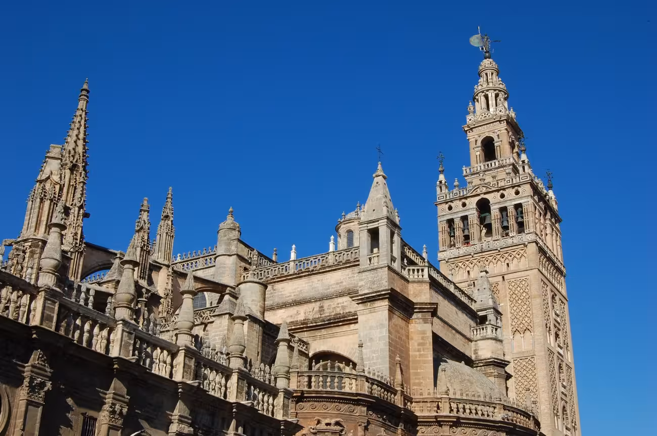 The majestic Giralda tower and Seville Cathedral against a clear blue sky, a highlight of Seville's historic tour.