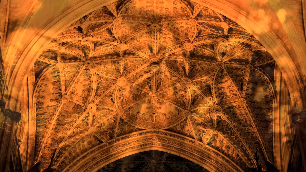 Ornate Gothic ceiling detail inside Seville Cathedral, showcasing elaborate stonework and craftsmanship.
