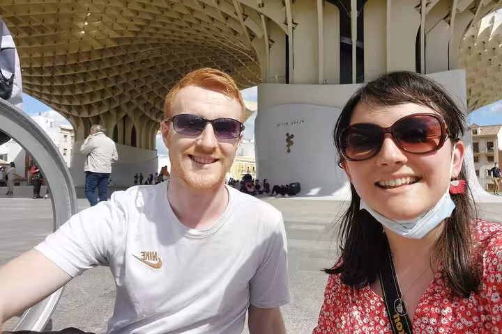 Two tourists smiling under the Metropol Parasol structure during a self-guided tour of Seville
