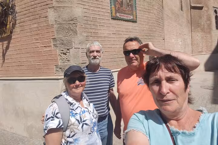Group of four tourists taking a selfie in front of a historic brick building in Seville
