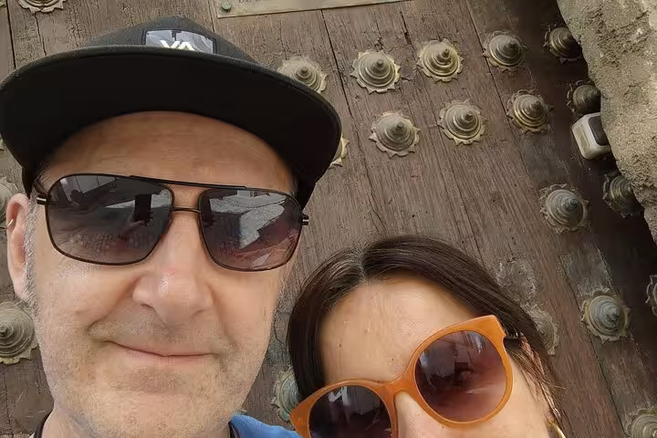 Couple taking selfie in front of ornate historic wooden door in Seville city tour