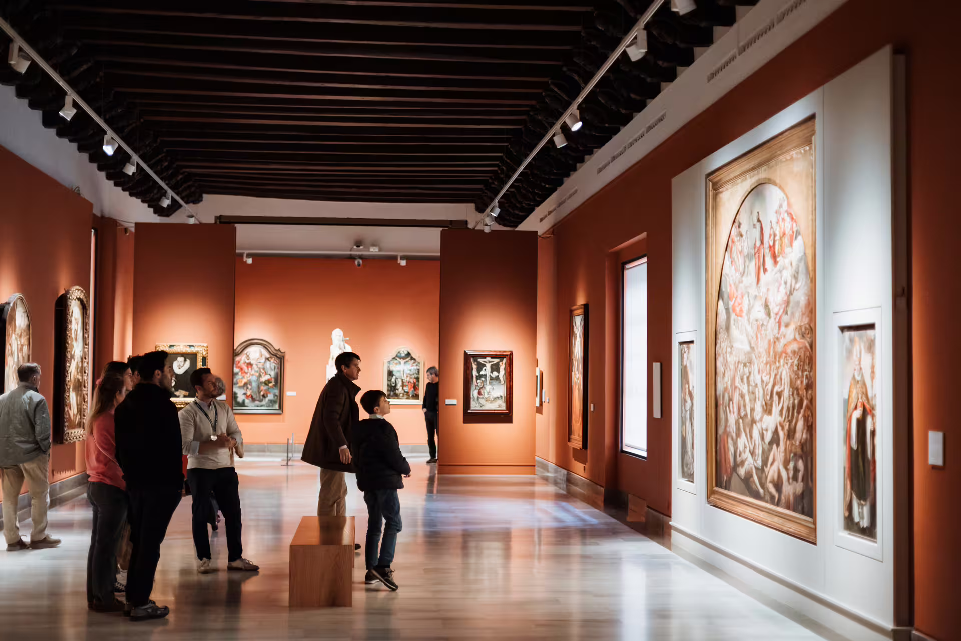 Visitors explore vibrant galleries in Seville's Fine Arts Museum, showcasing classic paintings and rich cultural history.