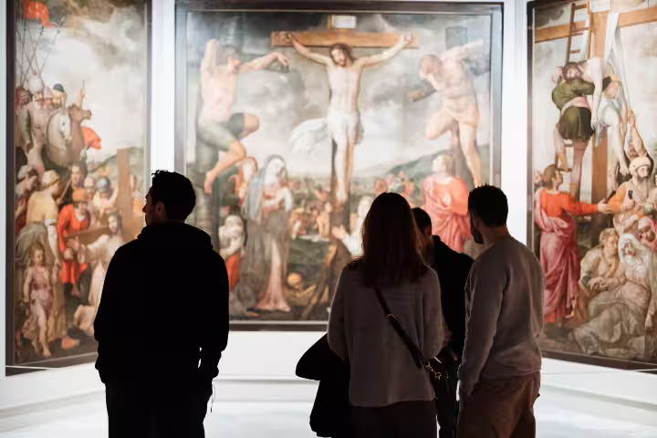 Visitors admire Renaissance paintings during a guided tour at Seville's Fine Arts Museum, highlighting cultural and historical art.