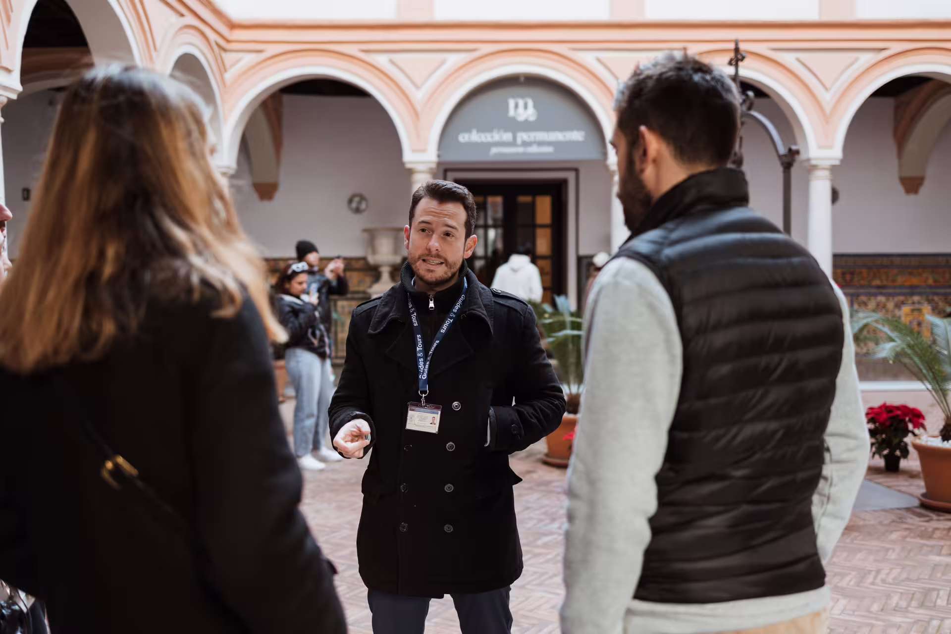 Tour guide leading a group at Seville's Fine Arts Museum, showcasing art and architecture in a historic courtyard setting.