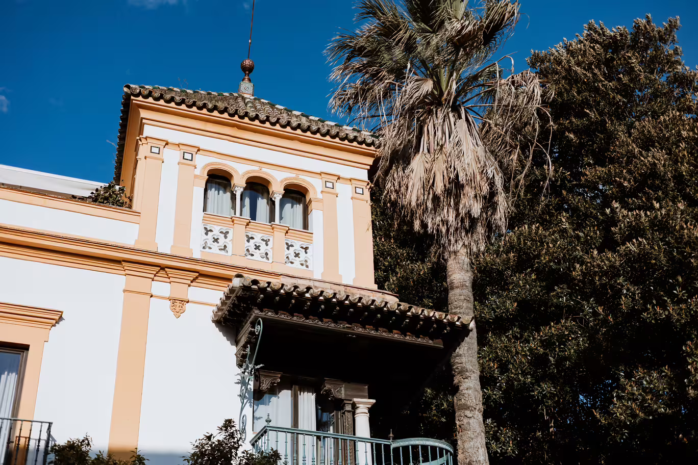 Historic architecture in Seville's Jewish Quarter with palm tree and traditional Spanish design elements.