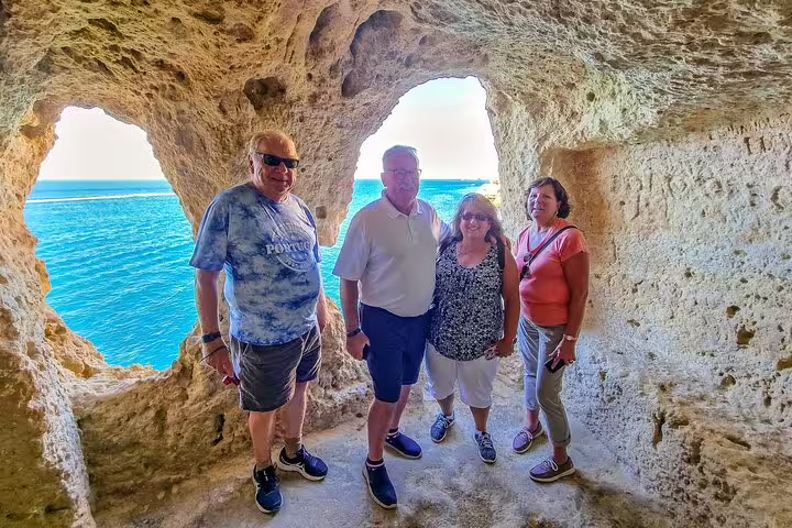 Travelers enjoy scenic Algarve cave views during Seville to Lisbon transfer, showcasing Portugal's coastal beauty and adventure.
