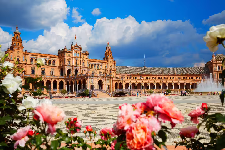 Plaza de España in Seville with vibrant flowers and dramatic skies, perfect for a scenic small group walking tour.