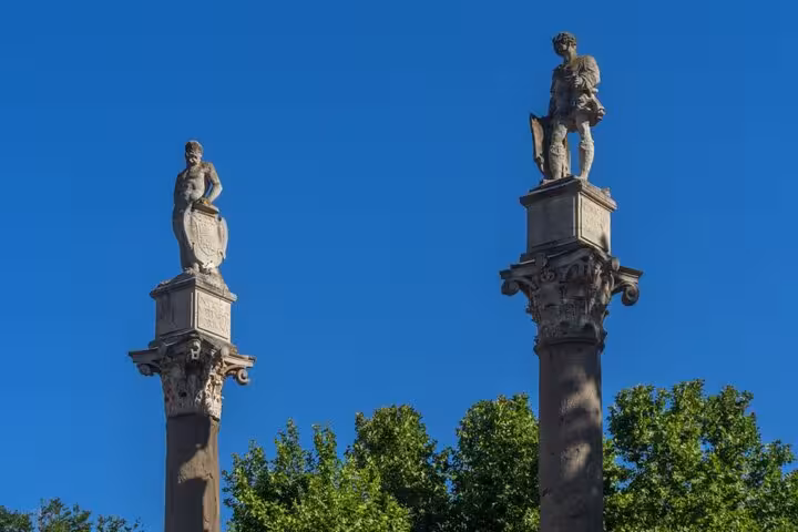 Two ancient Roman columns with statues in Seville under a clear blue sky