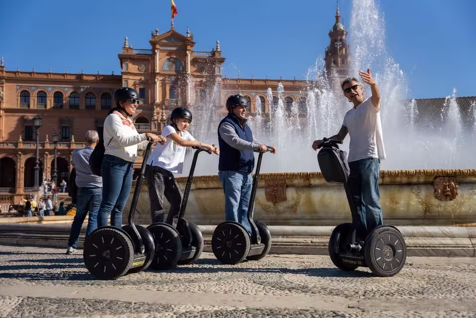 Tour group on Segways exploring Seville's Plaza de España with a stunning fountain backdrop.