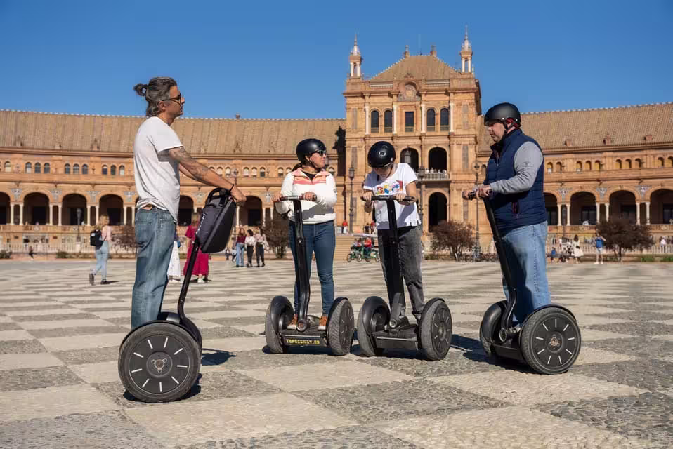 Group enjoying a Segway tour in front of Seville's Plaza de España under a clear blue sky.