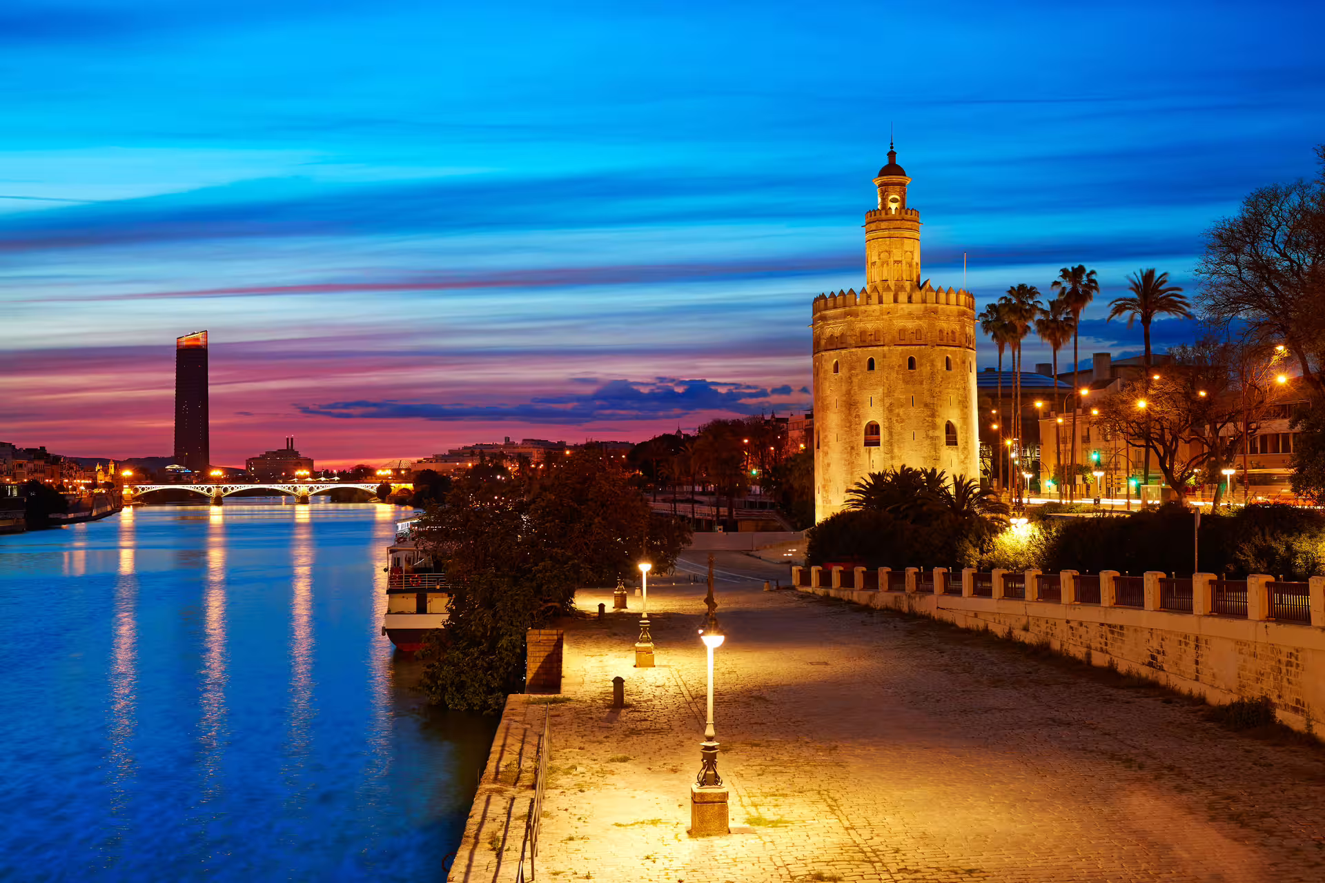 Illuminated Torre del Oro at sunset along the Guadalquivir River, setting for the Seville Mysterious and Paranormal Tour.