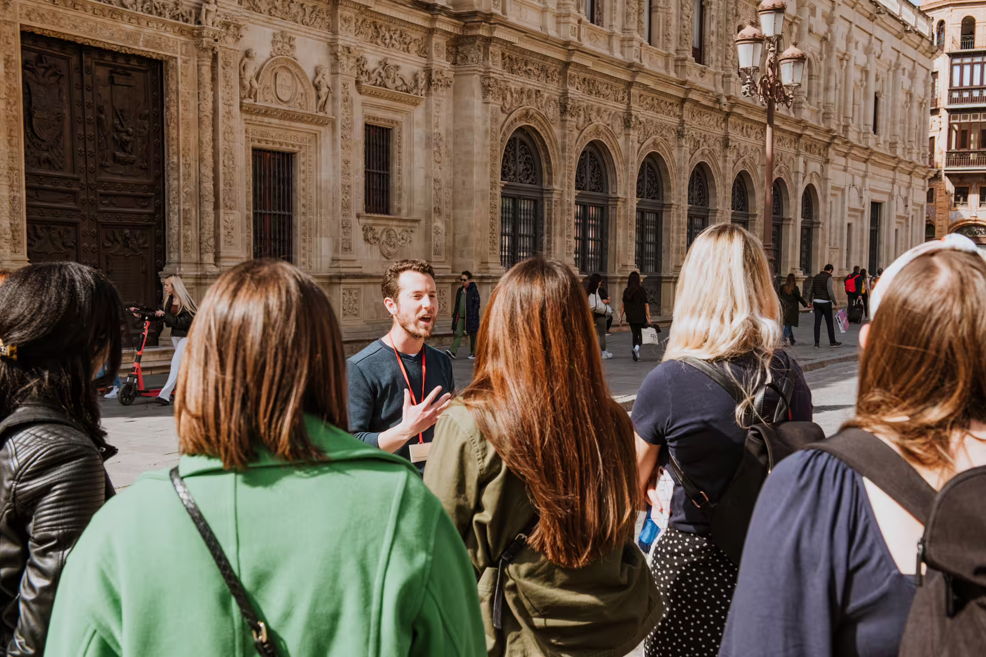 Tour guide leading a small group through historic Seville, showcasing stunning architecture on a sunny walking tour.