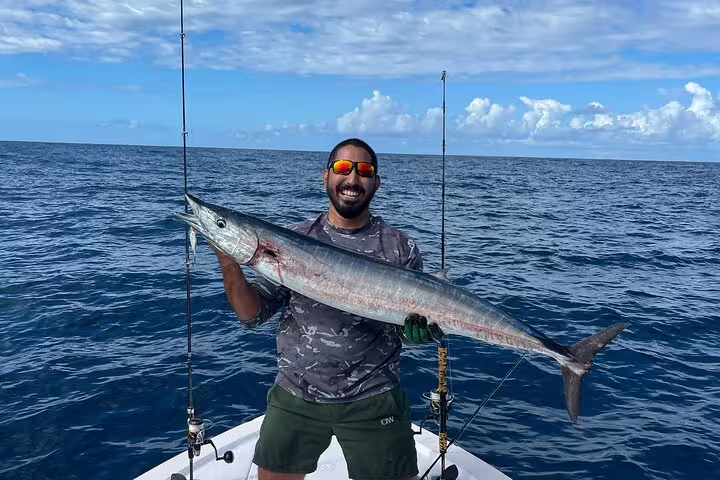 Angler proudly holding a large fish on a fishing boat in the vibrant waters of Seychelles, ideal for big game fishing.