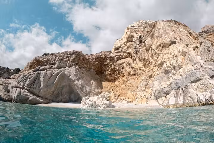 Turquoise Aegean Sea lapping a hidden white-sand cove and rugged cliffs near Seychelles Beach on Ikaria boat tour