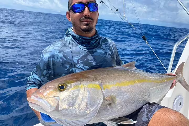Fisherman holds a sizable fish caught off the coast of Seychelles, showcasing a successful deep-sea adventure.