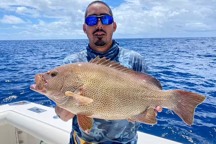 Excited angler presents a freshly caught fish against the stunning backdrop of Seychelles waters.