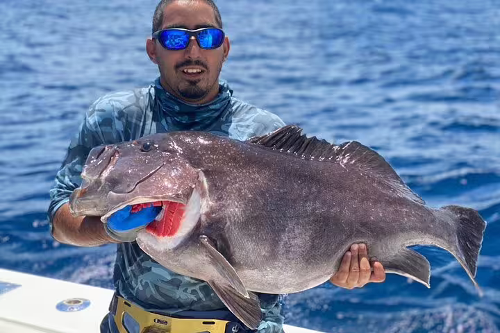 Angler proudly displays a large catch during a Seychelles fishing trip under sunny skies.